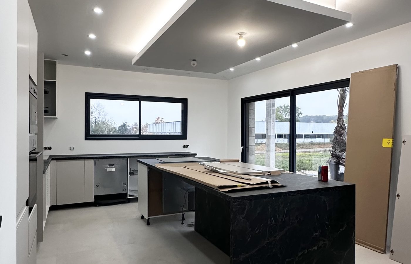 Pose de cuisine moderne par AB Rénovation - îlot marbre noir et faux plafond éclairé, Besançon Dijon